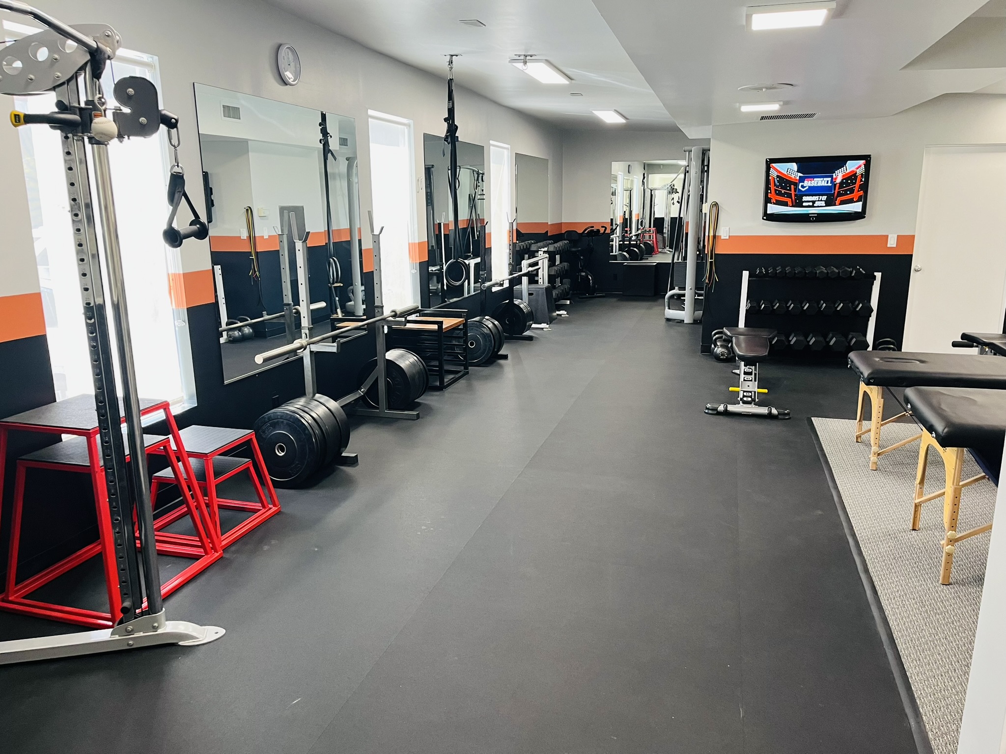 Interior of the gym at Premier Body Method Sports Medicine and Chiropractic office, equipped with a variety of weights and workout machines.